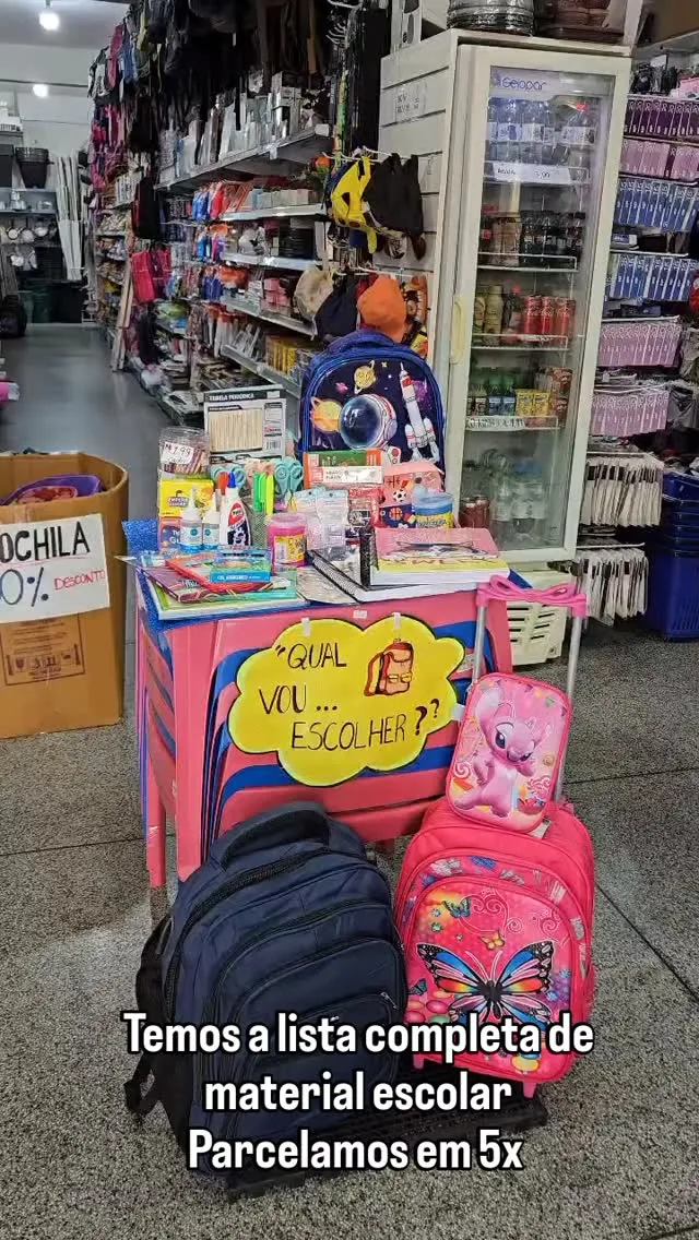 Expositor de mochilas com a placa “Temos a lista completa de material escolar”